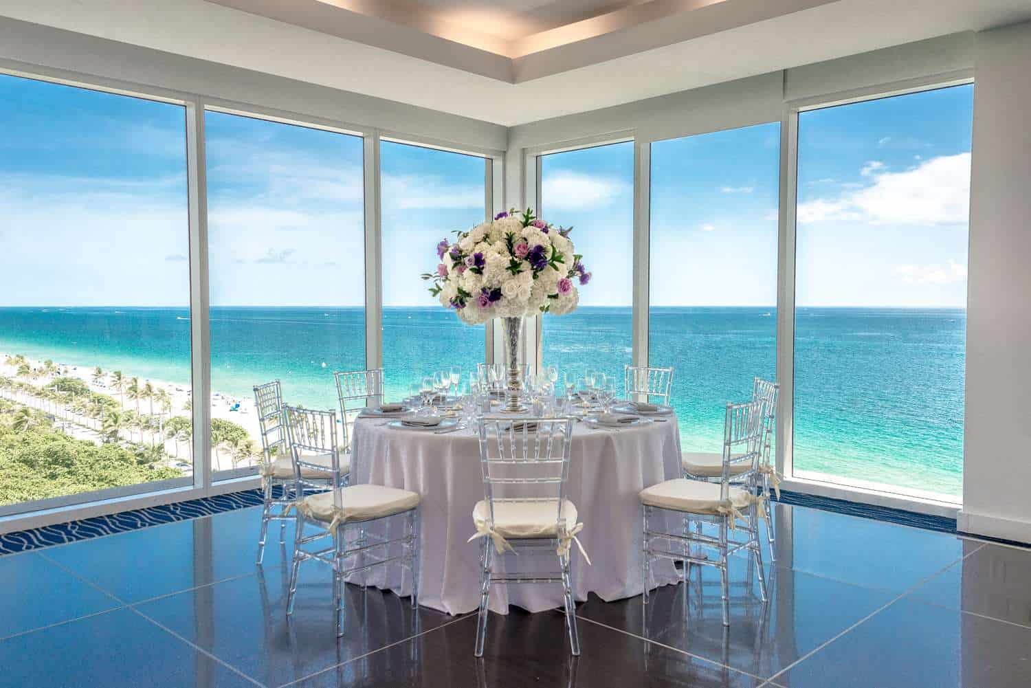 Table with floral centerpiece and ocean view windows.