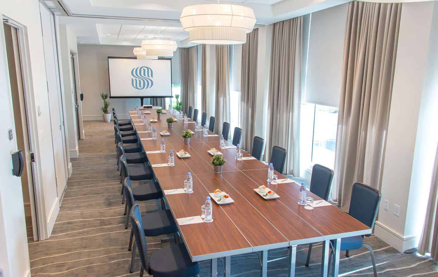 Spacious boardroom with large table and presentation screen.