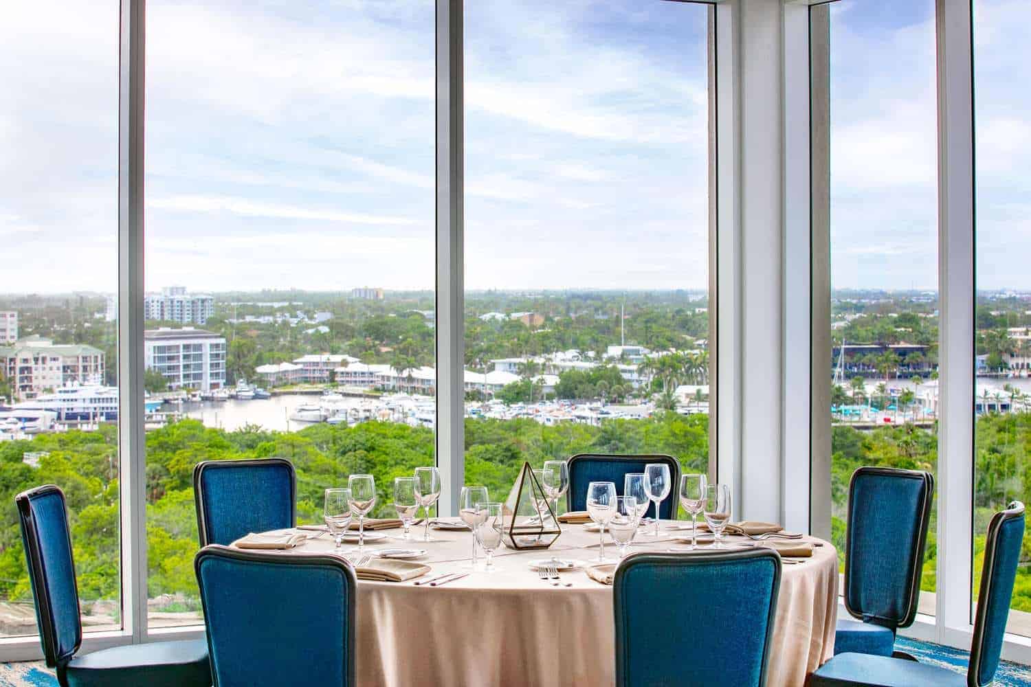 Dining table by floor-to-ceiling windows with scenic view.