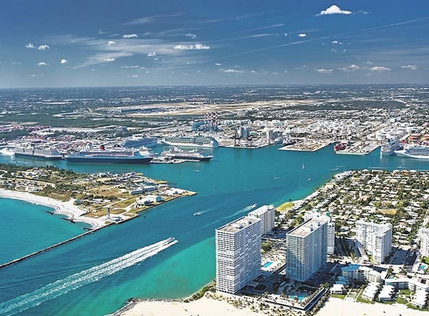 Aerial view of coastal city with boats and skyscrapers.