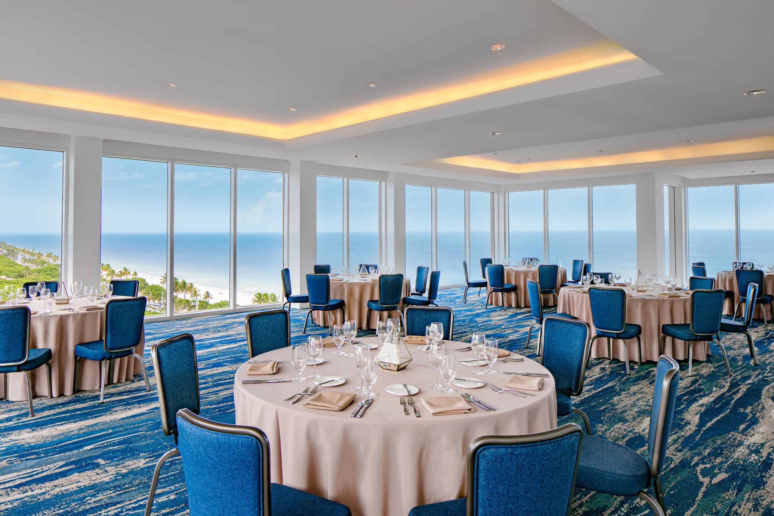 Banquet hall with ocean views and blue chairs.