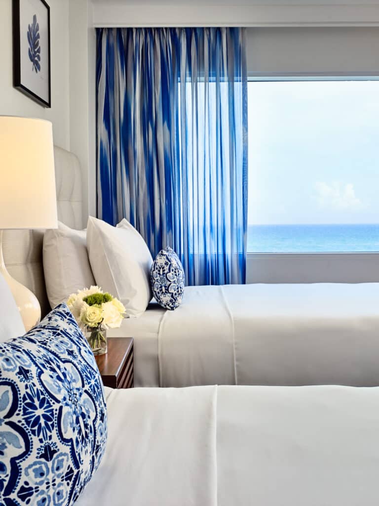 Hotel guestroom with two beds and an ocean view.