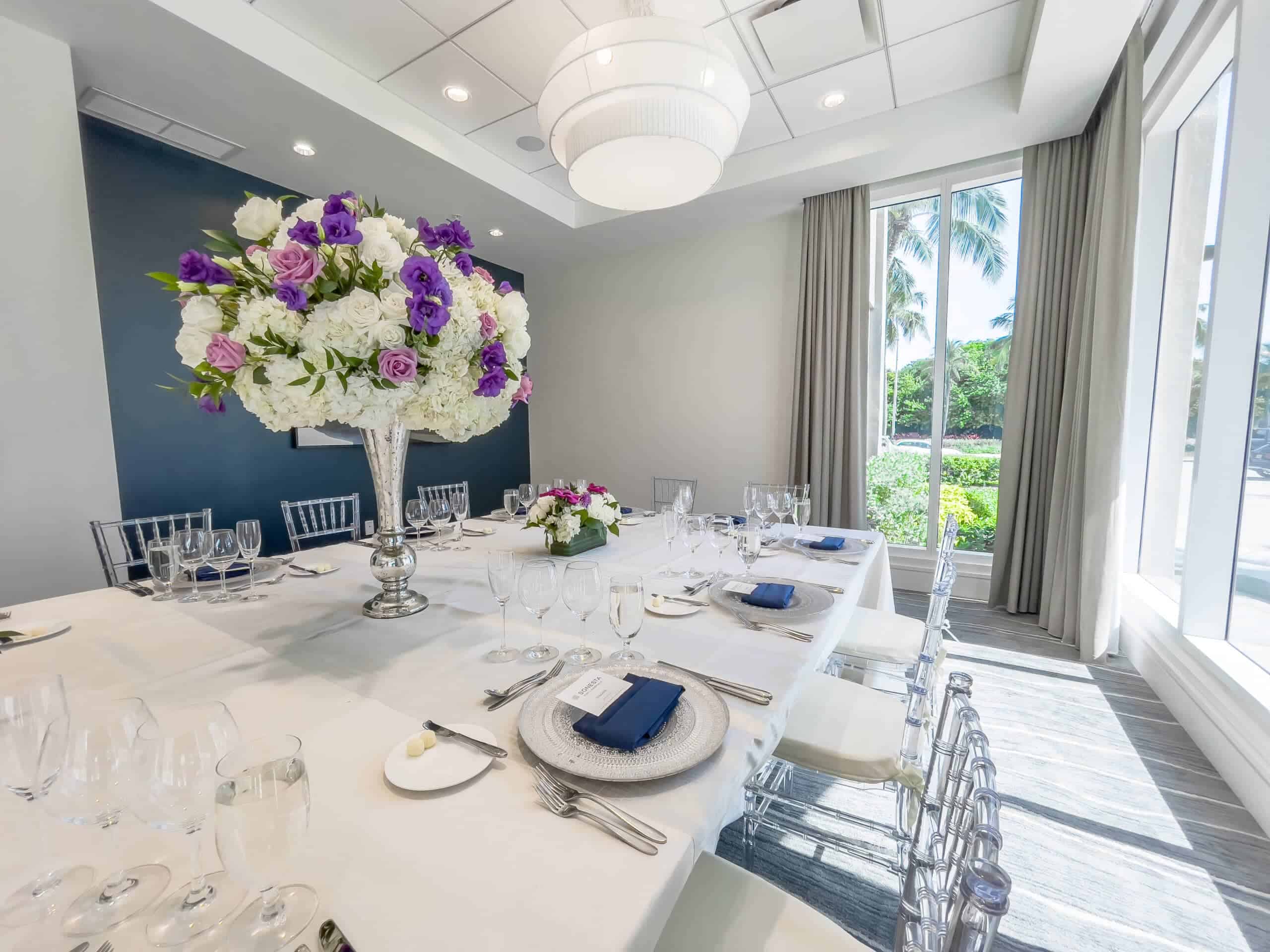 Formal dining table with tall flower arrangement centerpiece.