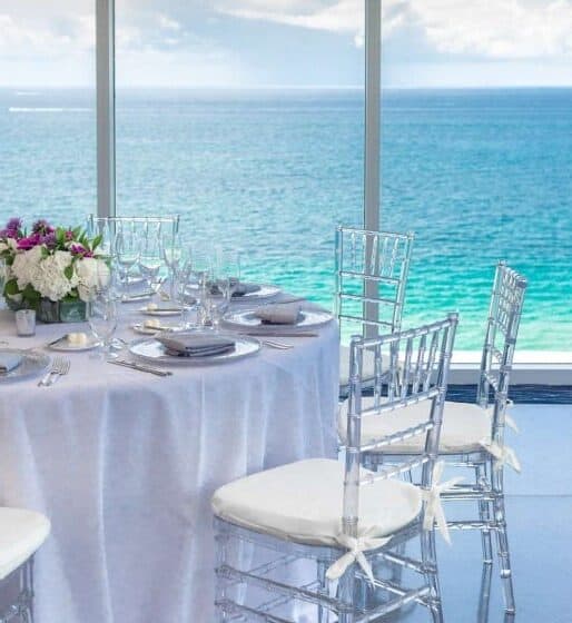 Table setup with ocean view and transparent chairs.