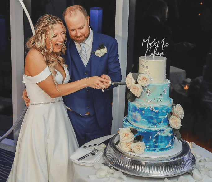 Bride and groom cutting a blue, multi-tiered wedding cake.