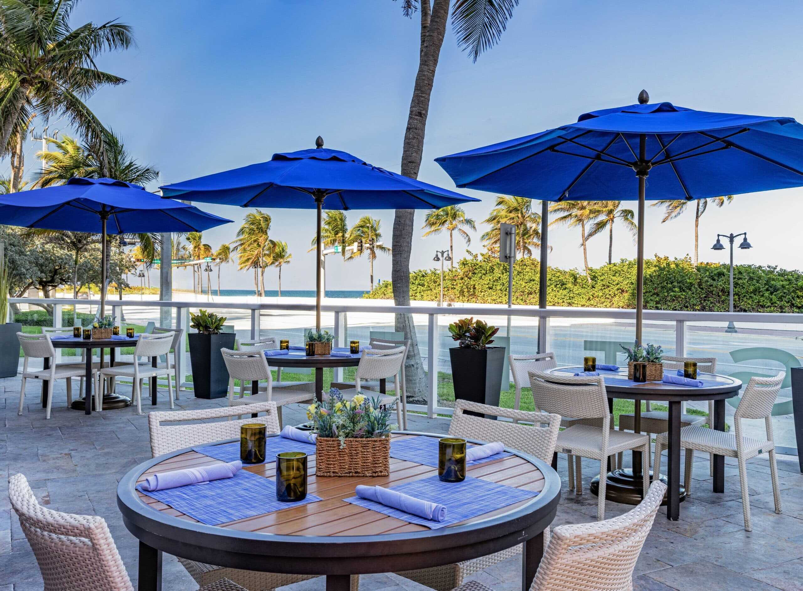 Outdoor event area with tables and palm trees.