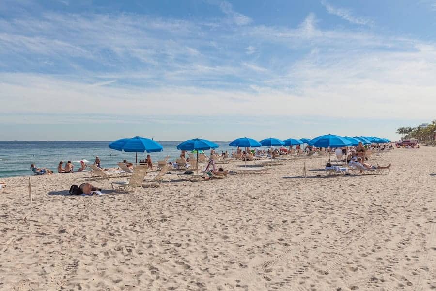 View of the beach with blue umbrellas and lounge chairs.